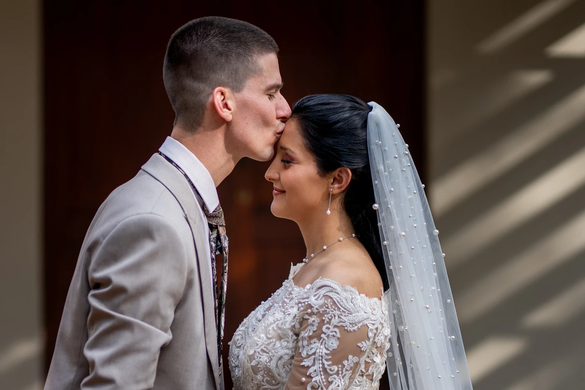 Groom kissing the bride on the forehead